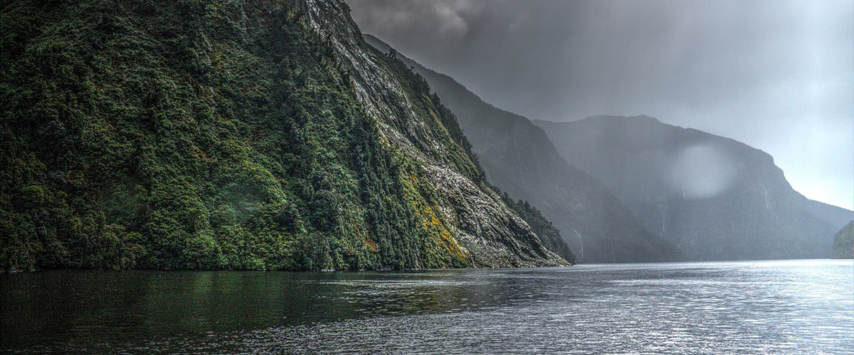 Blick auf einen Teil des Wassers des Doubtful Sound Fjords, mit dunklen Regenwolken am Himmel